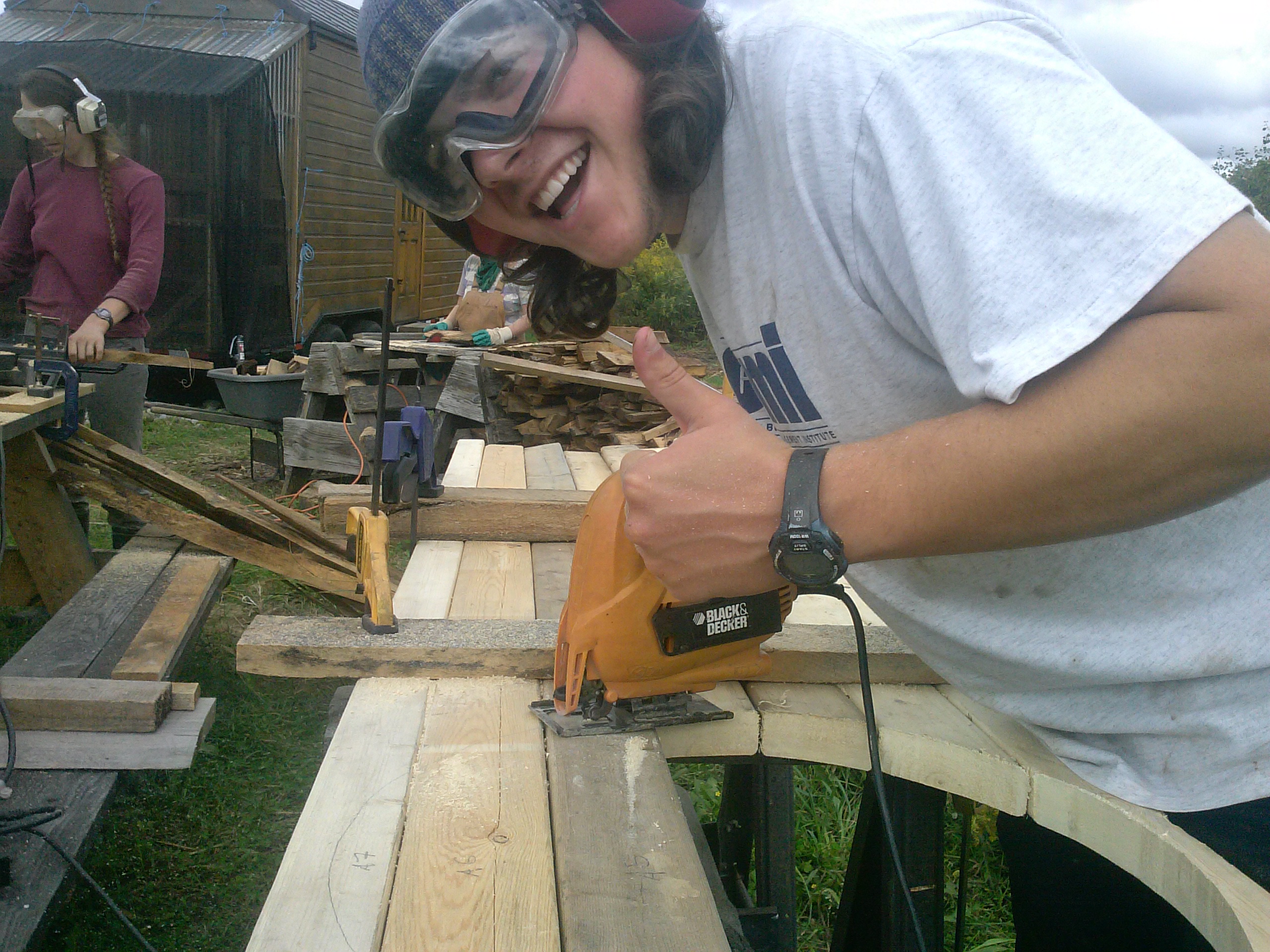 Permaculture intern using jigsaw to cut a circle out of wood